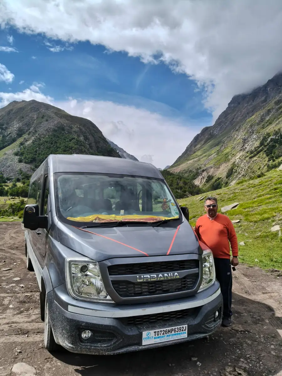 Gemini Urbania 12 seater parked in a green Himachal valley with its driver