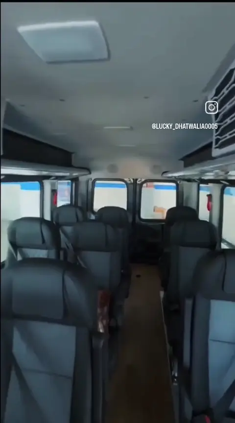 Rows of reclining seats, large windows and roof AC vents inside the Urbania